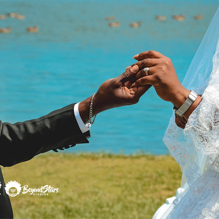 Groom taking the bride's hand, wedding rings on display